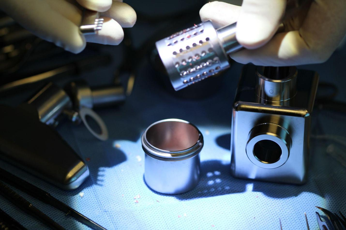 A pair of gloved hands holding dental equipment under a light