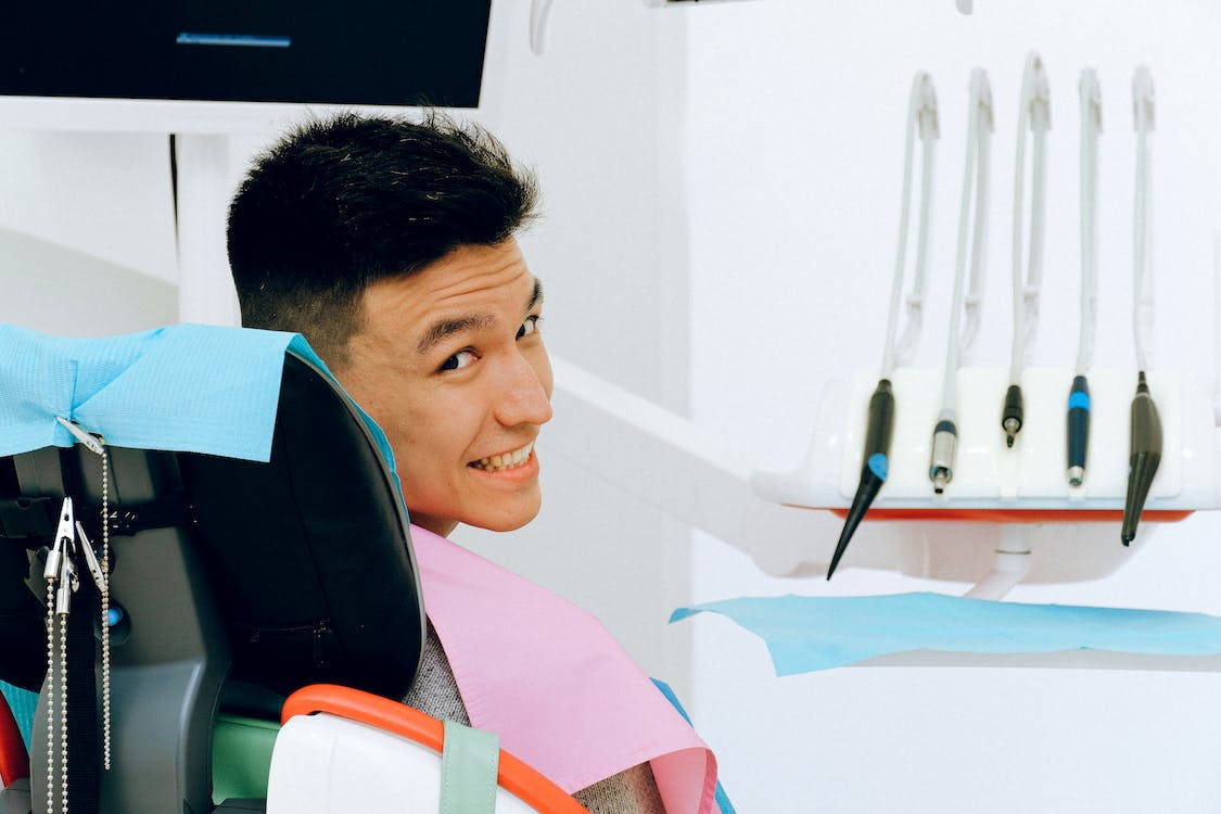 A person smiling while seated next to dental tools