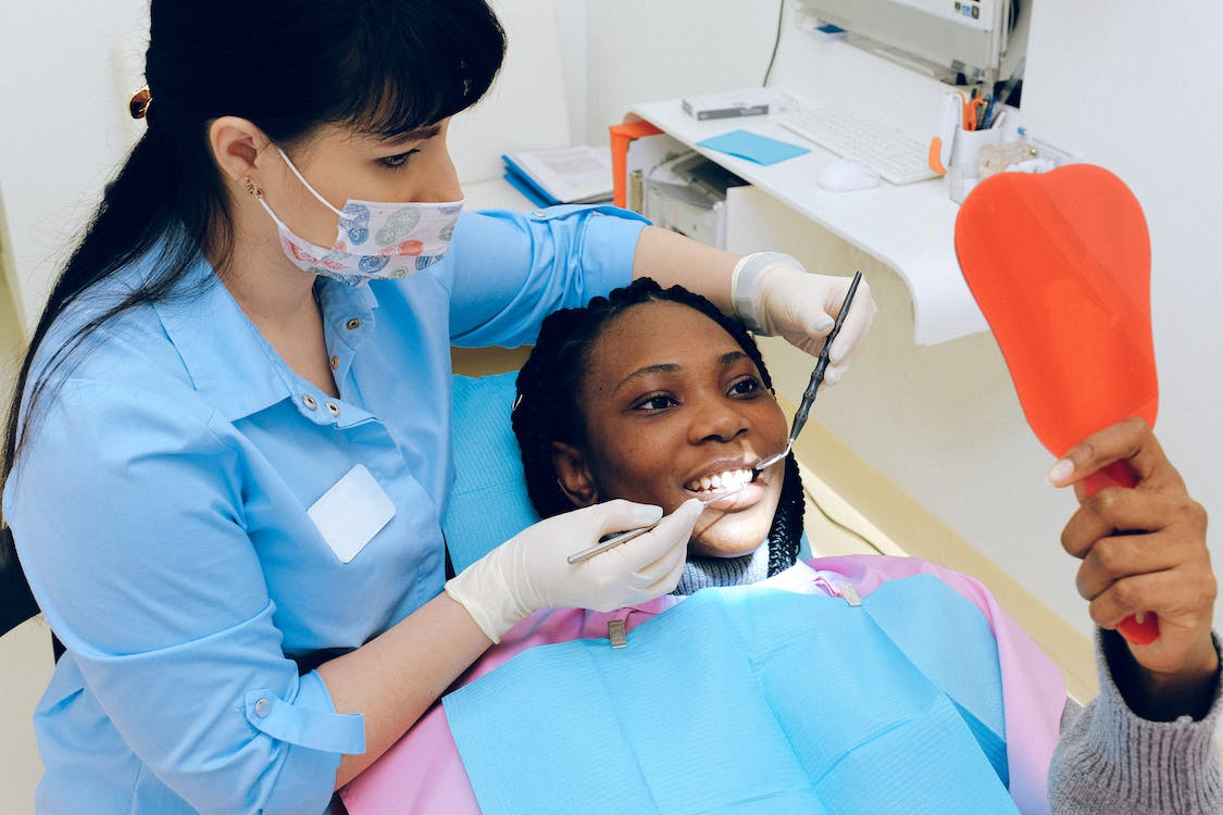 A dentist helping a patient view their teeth in a mirror