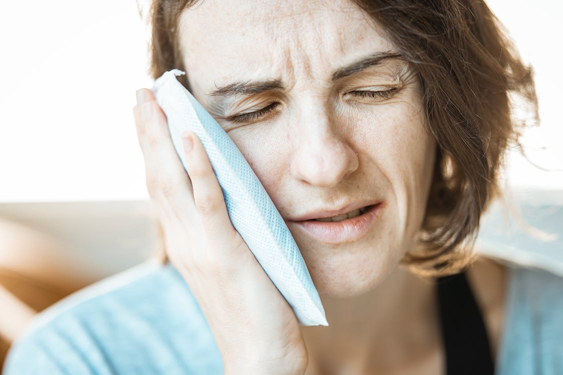 A person putting a cold compress on their cheek