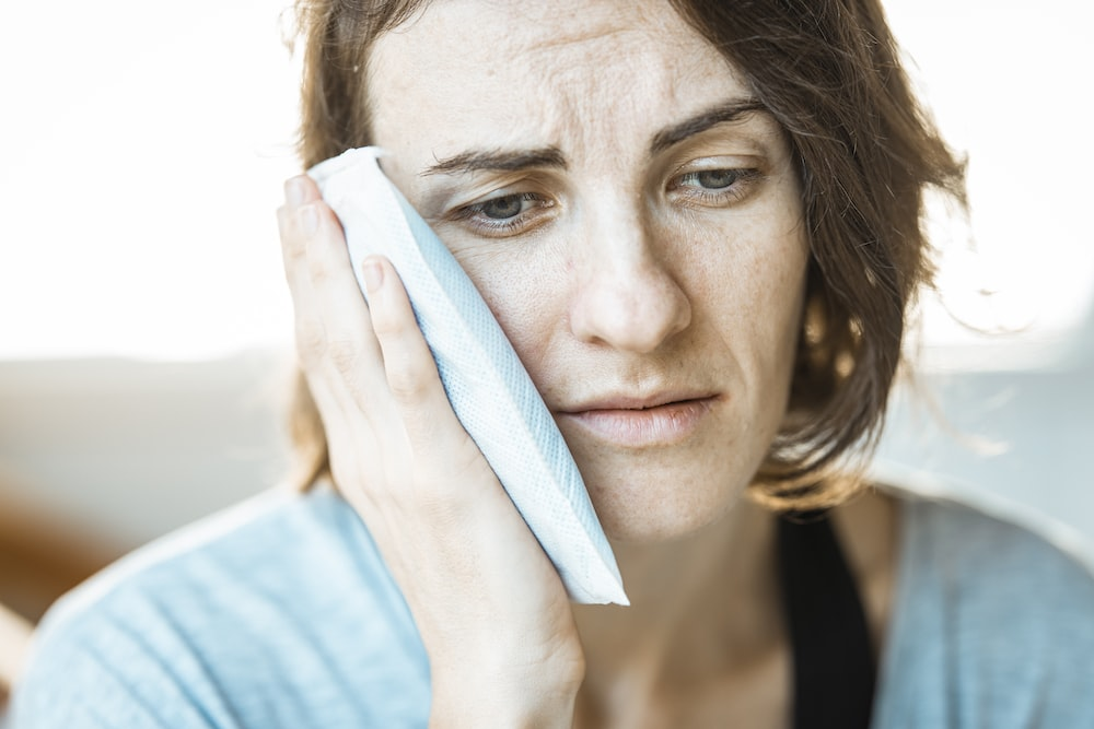 Woman holding an icepack near her face