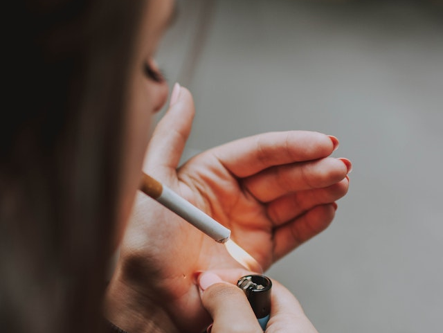 An individual lighting a cigarette