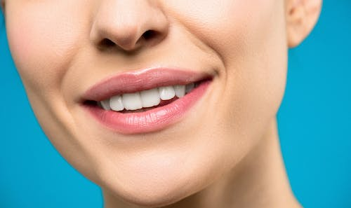 Close-up photo of a woman with pink lipstick smiling, radiating confidence and positivity.